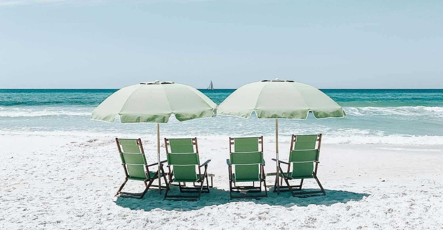 Una foto clara de sillas verdes bajo sombrillas en la arena de la playa